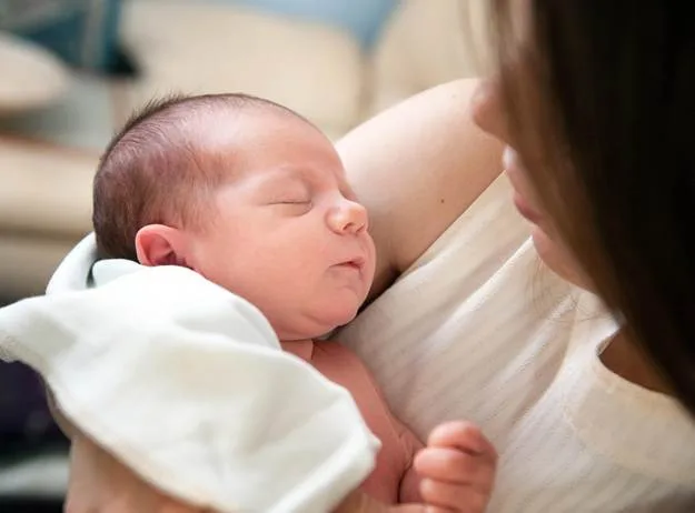 A night nurse holding a sleeping newborn